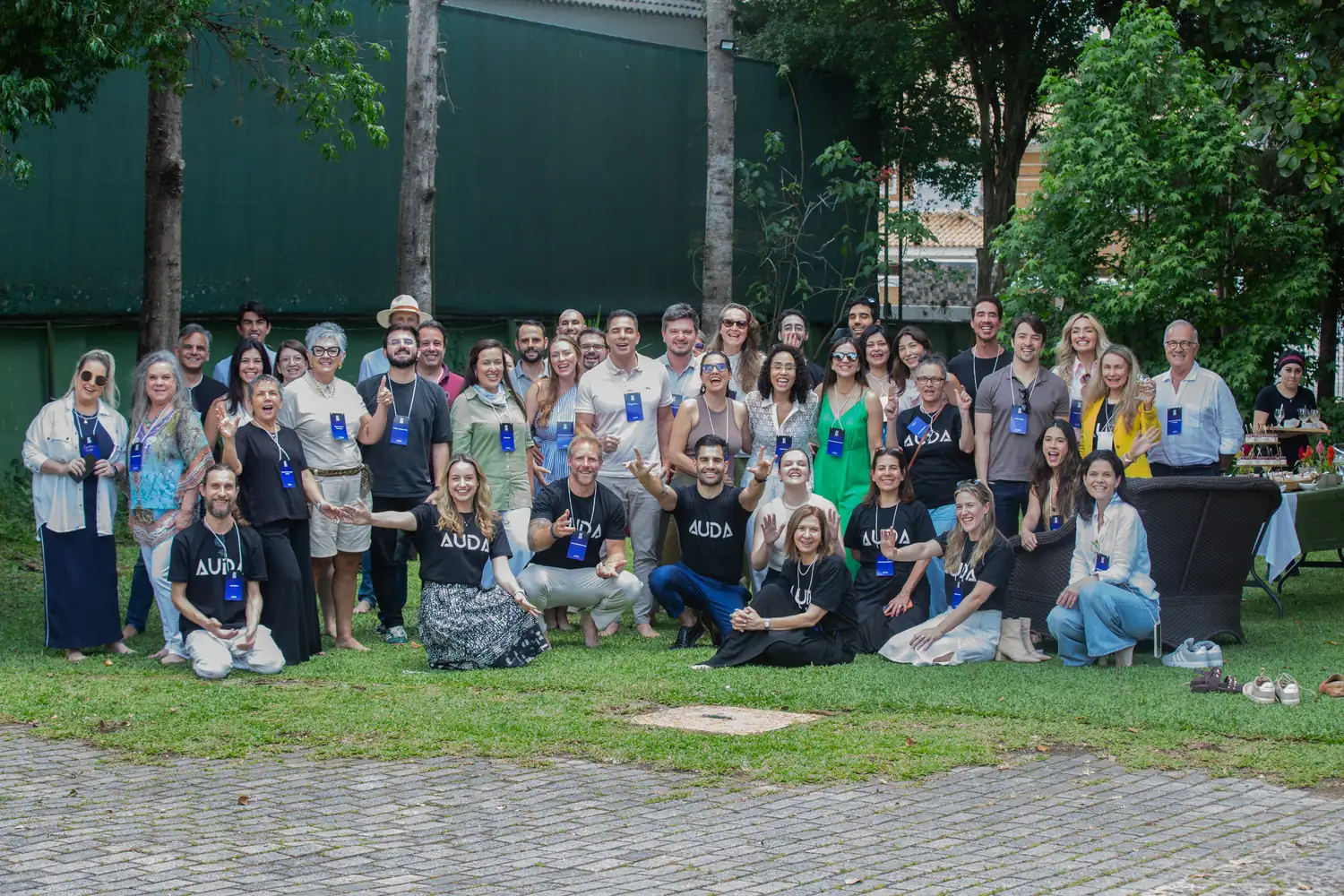 Foto de grupo com cerca de quarenta participantes e facilitadores reunidos no jardim no encerramento de uma imersão.