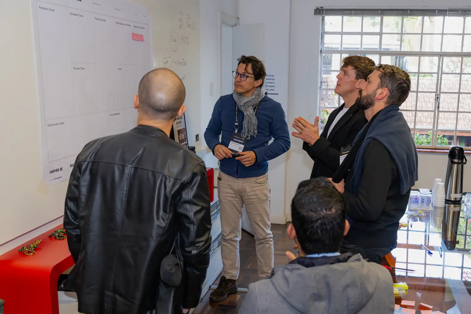 Participantes em pé discutindo o canvas colado na parede, aplicando o método ao próprio negócio.