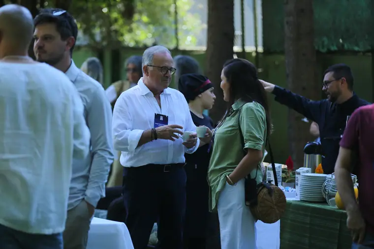 Dois participantes conversando de café na mão no jardim.