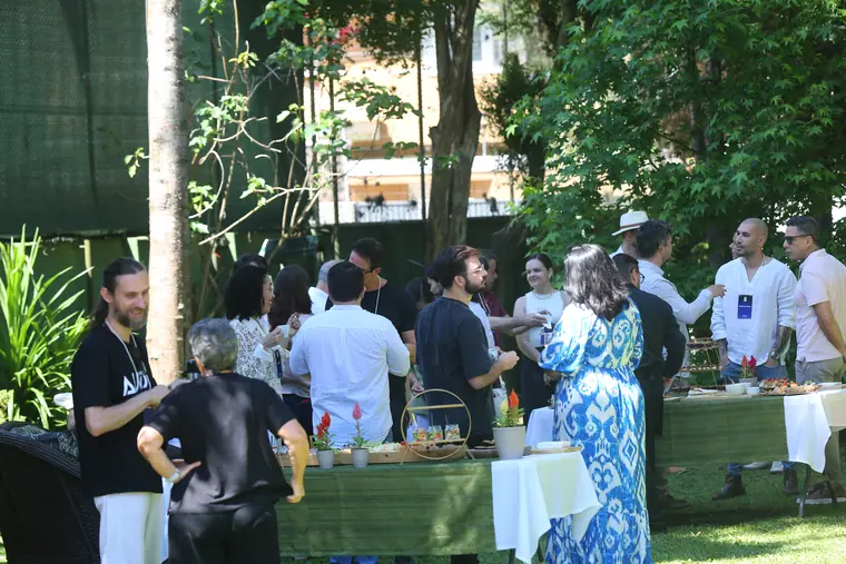 Intervalo no jardim, participantes em pé conversando em volta das mesas.